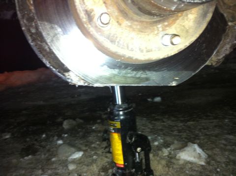 1994 Ford Bronco - A hydraulic jack is holding up a vehicle's brake rotor.
