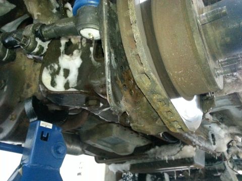 1994 Ford Bronco - Undercarriage view shows a vehicle's brake assembly and suspension, with visible rust and ice.