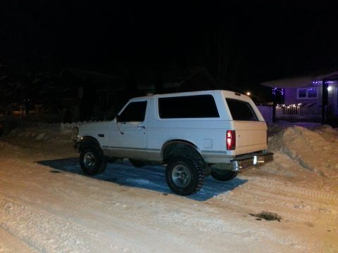 1994 Ford Bronco - White Ford Bronco parked in a snowy driveway at night. The vehicle appears to have a lifted suspension.