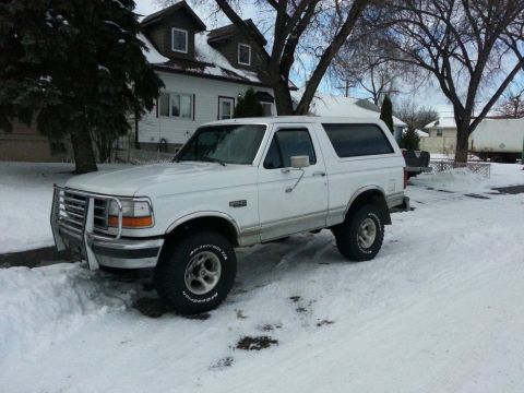 1994 Ford Bronco - A white 1994 Ford Bronco equipped with a brush guard sits in a snowy driveway.