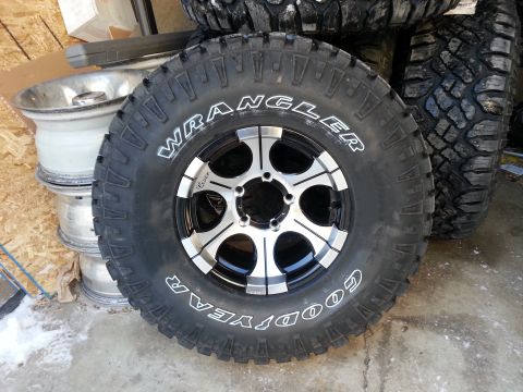 1994 Ford Bronco - A close-up of a Goodyear Wrangler tire mounted on a multi-spoke alloy wheel, with other tires visible in the background.