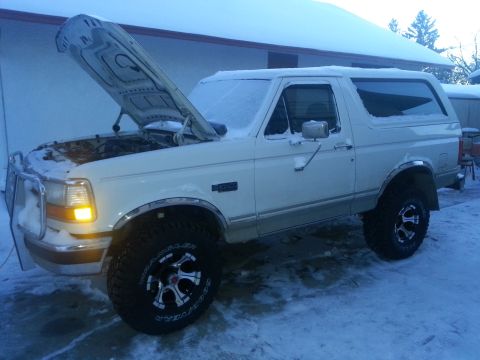1994 Ford Bronco - White Ford Bronco with hood open in snowy conditions, aftermarket wheels and a brush guard.