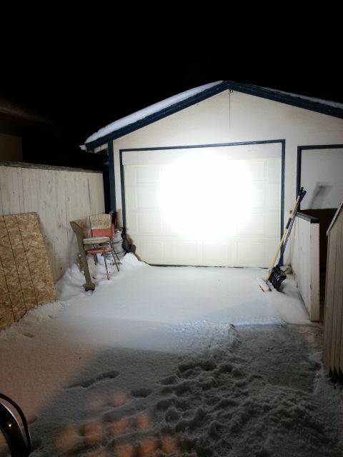 1994 Ford Bronco - A snowy scene in front of a garage door at night, with a shovel and broom leaning against the wall.