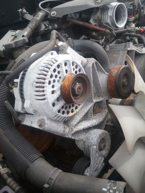 1994 Ford Bronco - Close-up view of a corroded engine alternator and associated pulleys.