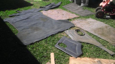 1982 Jeep Wagoneer - Car interior carpet and door panels are laid out on the grass for cleaning or replacement.