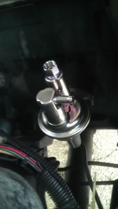 1982 Jeep Wagoneer - Close-up of a chrome-topped fuel pressure regulator or vacuum diaphragm component with wiring harness in an engine bay.