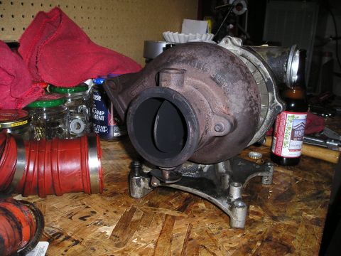 1997 Ford F-250 - Turbocharger assembly sits on a workbench next to red hoses and jars of hardware.