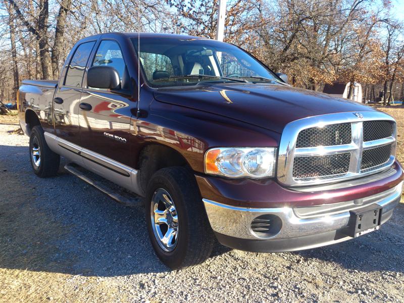 Maroon and silver Dodge Ram 1500 pickup truck, front 3/4 view, parked on gravel