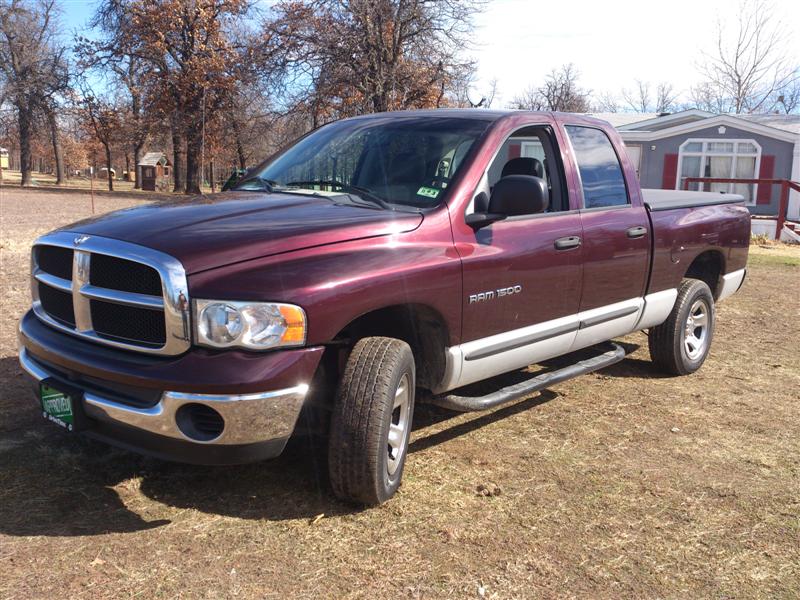 Maroon 2004 Dodge Ram 1500 pickup truck with a silver lower body and black tonneau cover, parked on dry grass