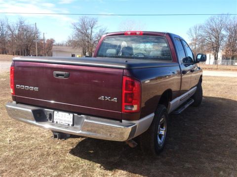 2004 Dodge 1500 - A maroon pickup truck is parked outdoors on a dry, grassy area under a clear blue sky.