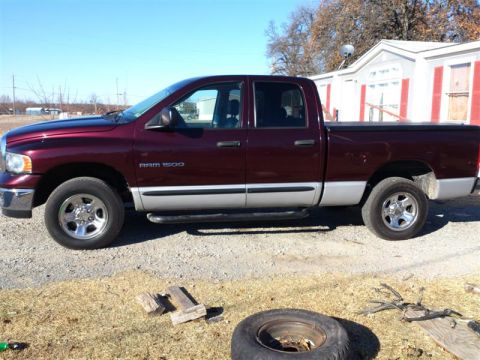 2004 Dodge 1500 - A maroon 2004 Dodge 1500 pickup truck is parked outdoors on a gravel surface.