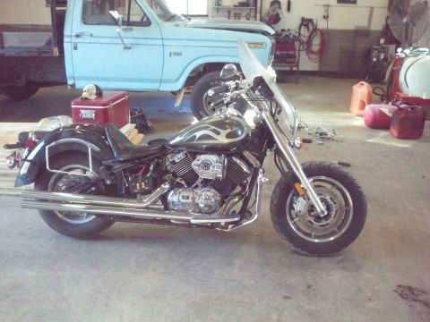 1995 Ford F-150 - A black motorcycle with flame decals sits in a garage next to a light blue truck.