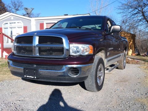 2004 Dodge 1500 - A maroon Dodge Ram pickup truck is parked in front of a house and a wooden shed.
