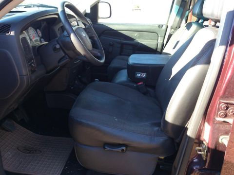 2004 Dodge 1500 - The interior of this 2004 Dodge 1500 features a dark cloth driver's seat, a black center console, and a clear view of the dashboard and ste…
