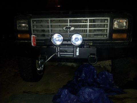 1986 Ford Bronco - Front view of a 1986 Ford Bronco a custom bumper with a winch and two large auxiliary lights mounted above the grille.