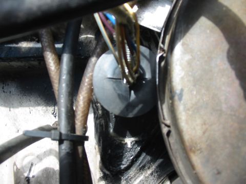 1992 Ford Bronco - A bundle of wires passes through a rubber grommet in the firewall, with hoses and other engine components visible.