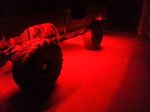 1978 Ford Bronco - Red underglow lights illuminate the tires and chassis of an off-road vehicle.