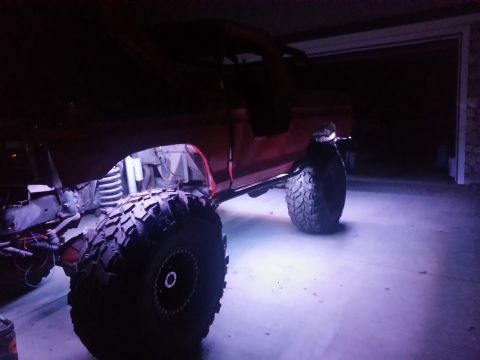 1978 Ford Bronco - This red SUV features oversized tires and custom underglow lighting, casting a purple hue on the ground.