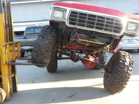 1978 Ford Bronco - Forklift lifting the front of a 1978 Ford Bronco, showing its large tires and suspension.