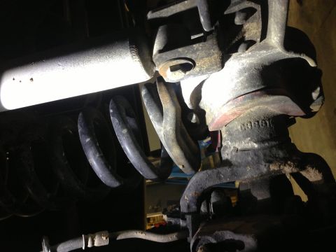 1996 Ford Bronco - Close-up view of vehicle suspension components, including a coil spring and shock absorber, showing signs of rust and wear.