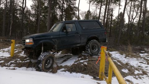 1995 Ford Bronco - This 1995 Ford Bronco navigates a challenging snowy incline in a wooded area.