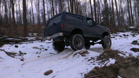 1995 Ford Bronco - Ford Bronco navigates a snow-covered path through a forest.
