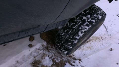 1995 Ford Bronco - A vehicle tire is stuck in the snow and mud, showing the tread pattern.