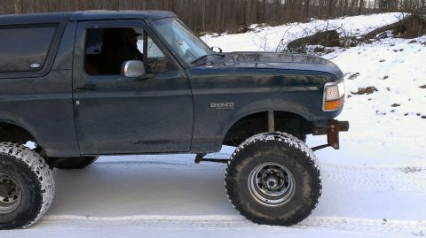 1995 Ford Bronco - Side view of a 1995 Ford Bronco with lifted suspension and large tires in a snowy environment.