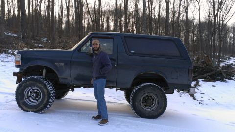 1995 Ford Bronco - A man stands beside a lifted Ford Bronco in a snowy, wooded landscape.
