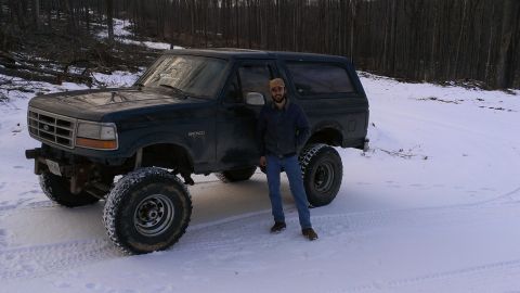 1995 Ford Bronco - A man stands next to a lifted Ford Bronco in a snowy, wooded area.