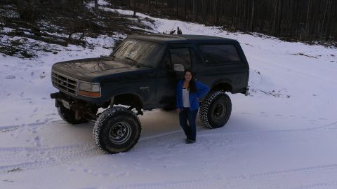1995 Ford Bronco - A lifted 1995 Ford Bronco sits in a snowy landscape, a person standing beside it.