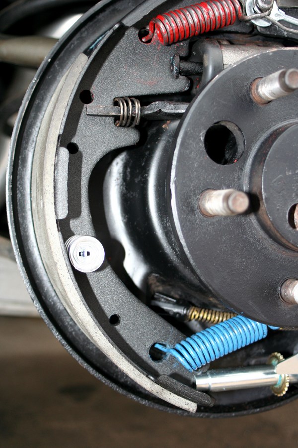 Close-up of a car's rear brake drum with shoes, springs, and adjuster visible