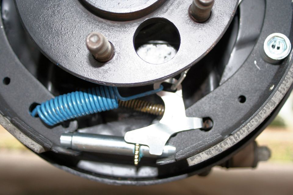 Close-up of a car's rear brake drum with shoes, springs, and adjuster visible
