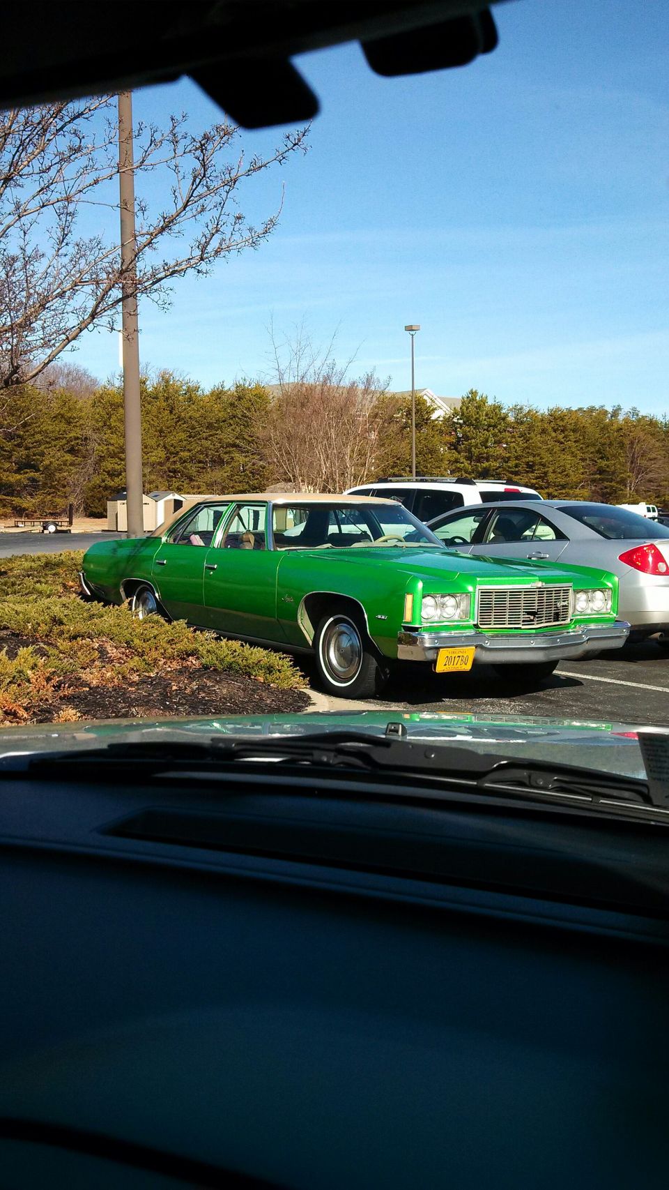 Green sedan with a white roof parked in a lot. License plate is yellow