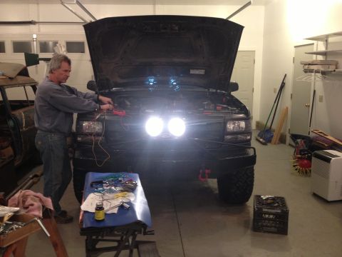 1996 Ford Bronco - A man is working on the engine of a 1996 Ford Bronco in a garage.