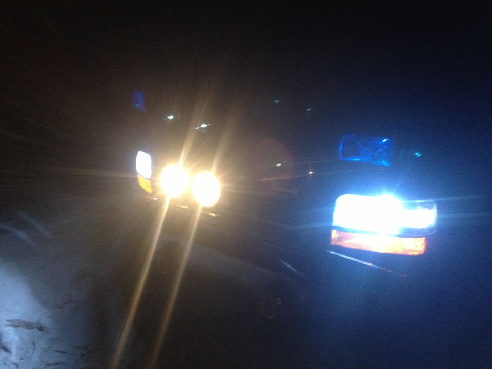 Headlights and grille of a dark vehicle at night