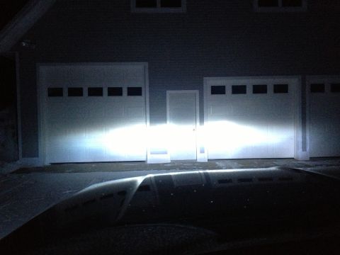 1996 Ford Bronco - Bright headlights illuminate a residential garage door, with a watermark indicating the source as Supermotors.net.