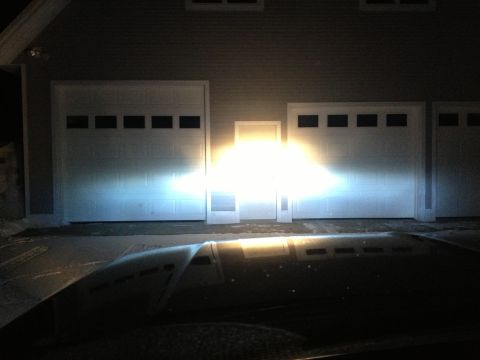 1996 Ford Bronco - Headlights shine brightly onto a set of garage doors, casting a wide beam across the scene.