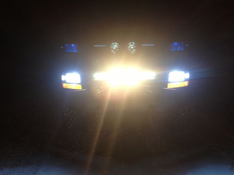 1996 Ford Bronco - Bright headlights and auxiliary lights illuminate the front of a truck at night.