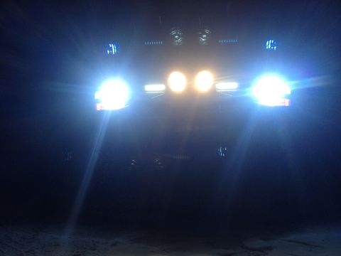 1996 Ford Bronco - Vehicle's front end illuminated by bright headlights and additional lights at night.