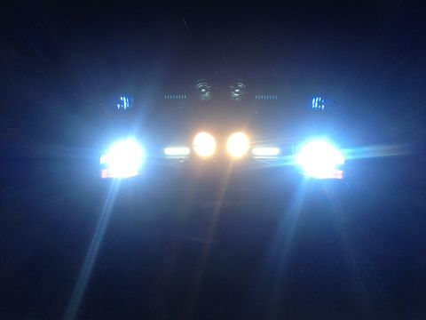 1996 Ford Bronco - The front of a vehicle is illuminated by its headlights and additional lights in the dark.
