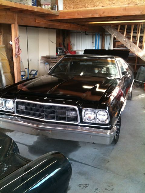 1975 Ford Ranchero - A black 1975 Ford Ranchero is parked inside a garage with its hood open.