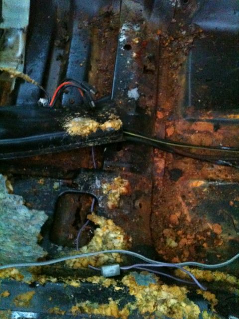 1975 Ford Ranchero - Severe rust and corrosion visible on the interior floor pan, with wiring and insulation exposed.