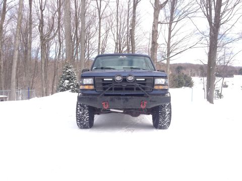 1996 Ford Bronco - A blue 1996 Ford Bronco is parked in the snow, an aftermarket bumper and off-road tires.