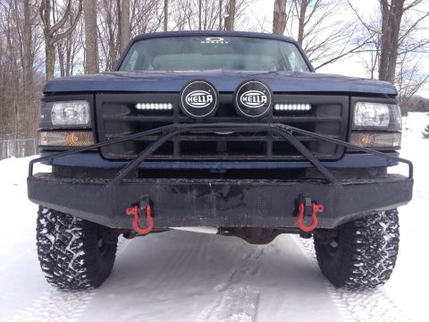 1996 Ford Bronco - Front view of a blue Ford F-Series truck with an aftermarket bumper and auxiliary lights during winter.