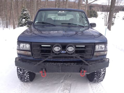 1996 Ford Bronco - A blue 1996 Ford Bronco is parked in a snowy area, a custom front bumper and auxiliary lights.