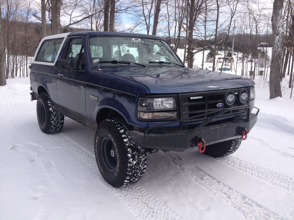 Blue 1996 Ford Bronco with white roof and aftermarket bumper in snow