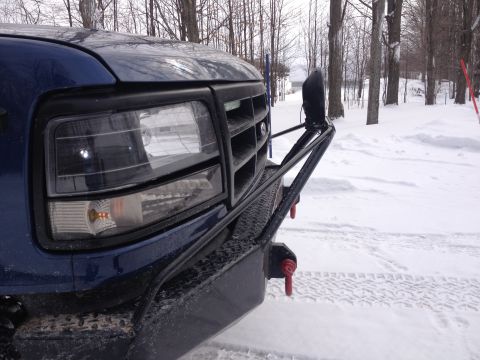 1996 Ford Bronco - Front view of a blue truck with an aftermarket bumper and winch, parked in a snowy landscape.