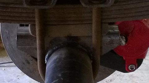 1995 Ford Bronco - This image shows a close-up view of a vehicle's rear axle and suspension components, including a red brake caliper.