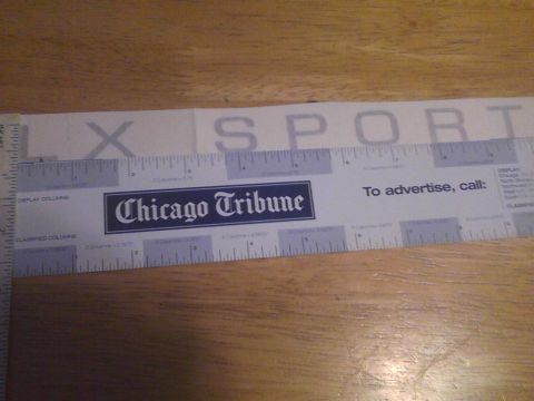2003 Ford Crown Victoria - A ruler with newspaper markings and text is laid out on a wooden surface.
